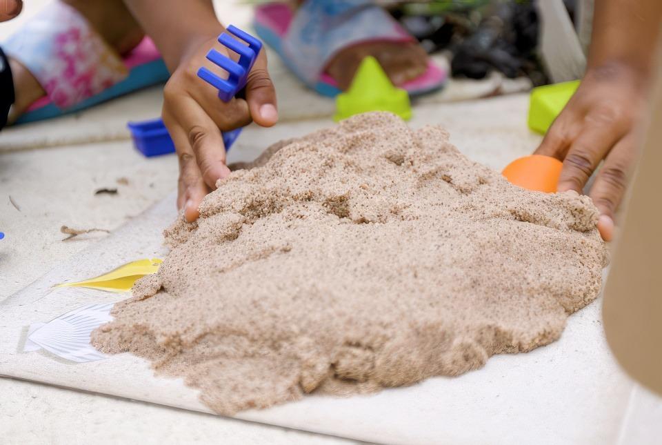 A child age 4-8 playing with sand as an educational activity.